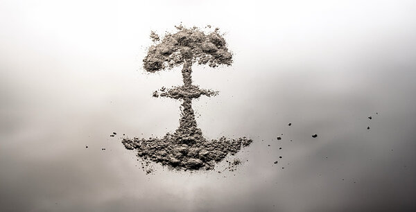 A formation of gray ash resembling a mushroom cloud or tree on a white to dark gray gradient background.